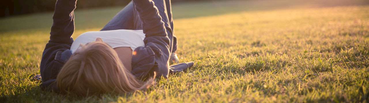 Kvinna på äng som ser ut att hålla i en surfplatta.